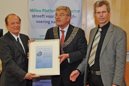 De heer Moors, voorzitter van de Raad van Bestuur van Ziekenhuis Amstelland ontvangt van Adriaan van Engelen van MPZ en burgemeester Jan van Zanen van de Gemeente Amstelveen het certificaat op het gouden niveau van de Milieuthermometer Zorg/Milieukeur. 
